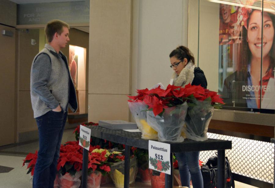 A student picks up a poinsettia that he reserved on Nov. 30 at Curtiss hall. The ISU Horticulture club is holding a poinsettia sale until Dec. 3 in various locations.