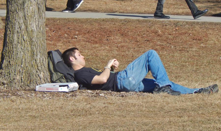 A student takes a nap in the warm spring air on central campus.