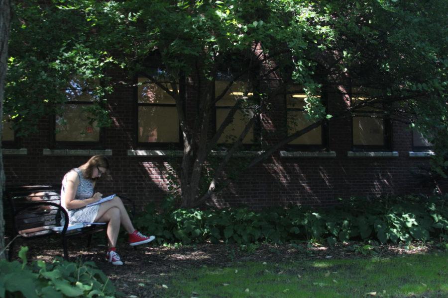 Emma Bade, freshman in elementary education, rests on a bench underneath a tree as the sunlight breaking through the leaves illuminates the Lagomarcino Courtyard.