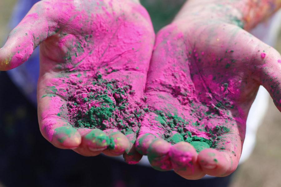 Fred Mace, sophomore in mechanical engineering, holds out a handful of colorful powdered paint used in the celebration. Typically, participates paint one another with this powder by rubbing it on faces, clothes, etc. 