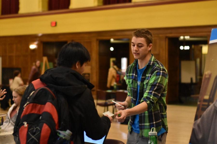 A representative from the Dance Marathon signs a students prize card at the Earth Day event on April 19, 2018.