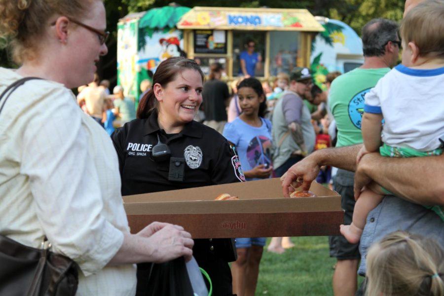 An Iowa State University police officer hands out donuts during the National Night Out event at Bandshell Park on Aug 1.