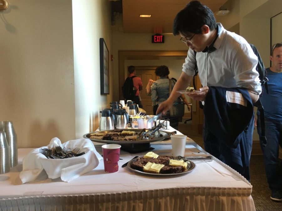 A symposium attendee takes a break to snack on brownies and coffee. 