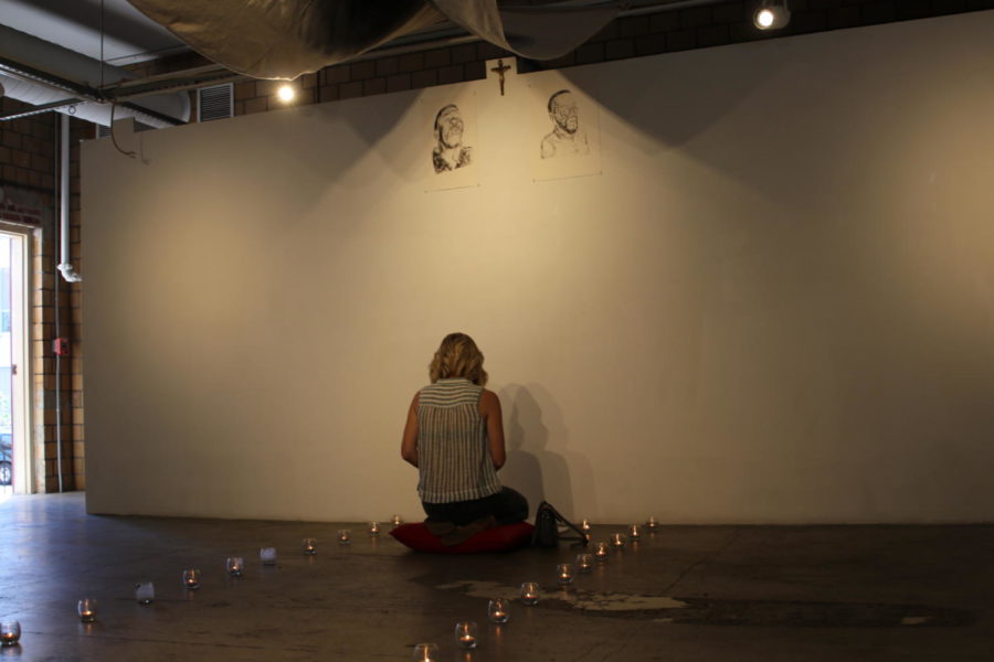 A visitor kneels in the gallery to write a prayer.