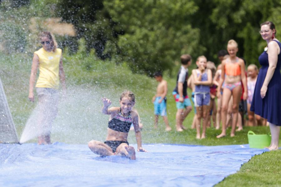 Kids play on a slip n slide made from a tarp and sprinklers during Reiman Gardens' Water Day July 13