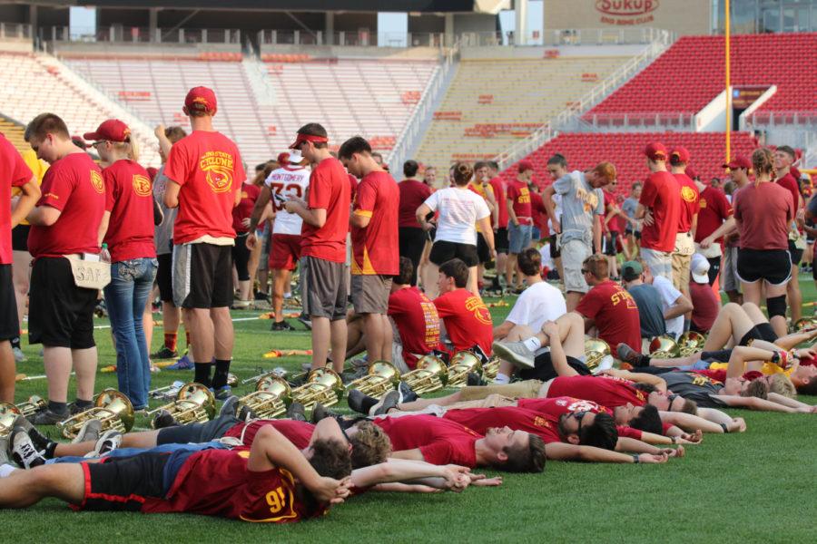 Members of the ISU Marching Band relax after practice prior to Victory Day starting at Jack Trice Stadium on Aug. 24.