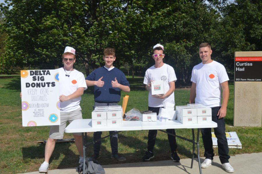 Brady Lange (sophomore), Joseph Kiernan (freshman), Nathaniel Dalton (freshman), and Camren Jones (junior) members of Delta Sig take advantage of the nice weather to sell donuts on central campus. The money raised will be given to the Youth and Service Shelters of Ames.