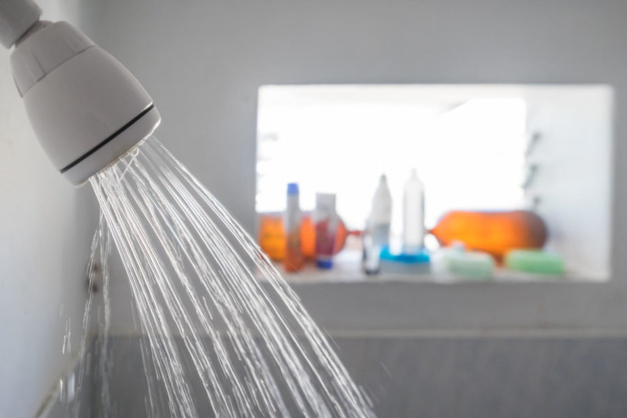 Close up of a shower head flowing water in a bathroom.
