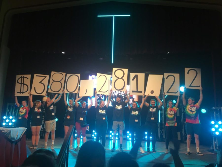 Dance Marathon participants hold up signs indicating the total amount raised at 2019s Dance Marathon event, $380,281.22.