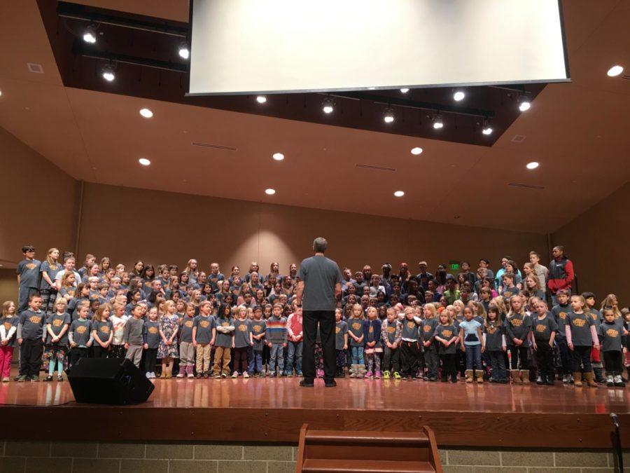 Students from Meeker Elementary, directed by Charles Grim, sing in the Ames Middle School auditorium.