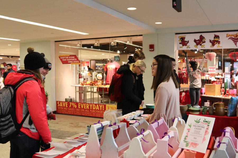 Senior Tuyen Le helps students select their products at the Valentines Day Pop-Up Art Sale. The sale runs from Feb. 11 to Feb. 14 from 10 a.m. - 2 p.m. outside the University Bookstore.