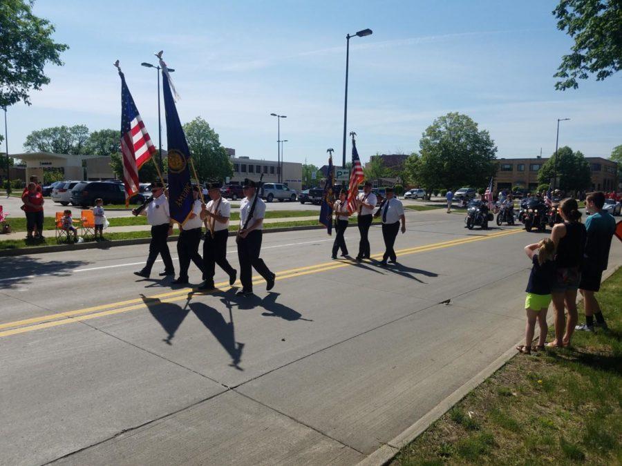 Veterans march in parade and hold flags to commemorate Memorial Day.