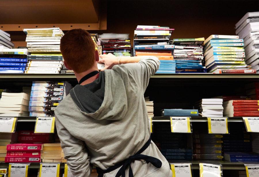 A student worker searches the shelves of the Memorial Union bookstore to complete students online pre-orders for textbooks and other required supplies.
