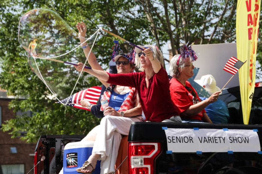 Members of the Senior Variety Show blow giant bubbles while riding though Downtown Ames during the 2018 Fourth of July Parade.