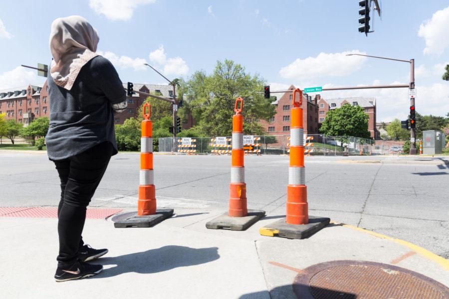 An Iowa State student waits at the corner of Welch Ave and Lincoln Way where a road is closed due to construction. 