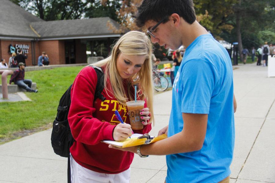 Evan Abramsky, then a sophomore in political science, right, helps Margo Wilwerding, then an undeclared freshman, left, register to vote in Story County, Iowa, in front of Parks Library on Sept. 25 2014