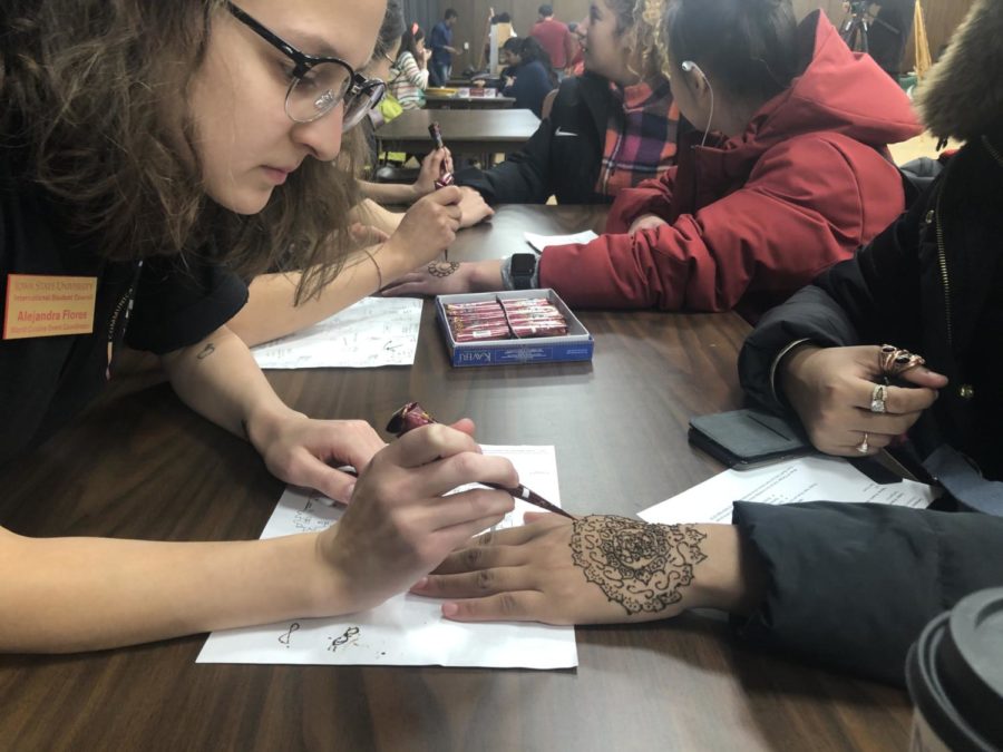 Alejandra Flores, sophomore in political science and history, applies henna to an attendees hand at the Bazaar and Game Night event Monday.