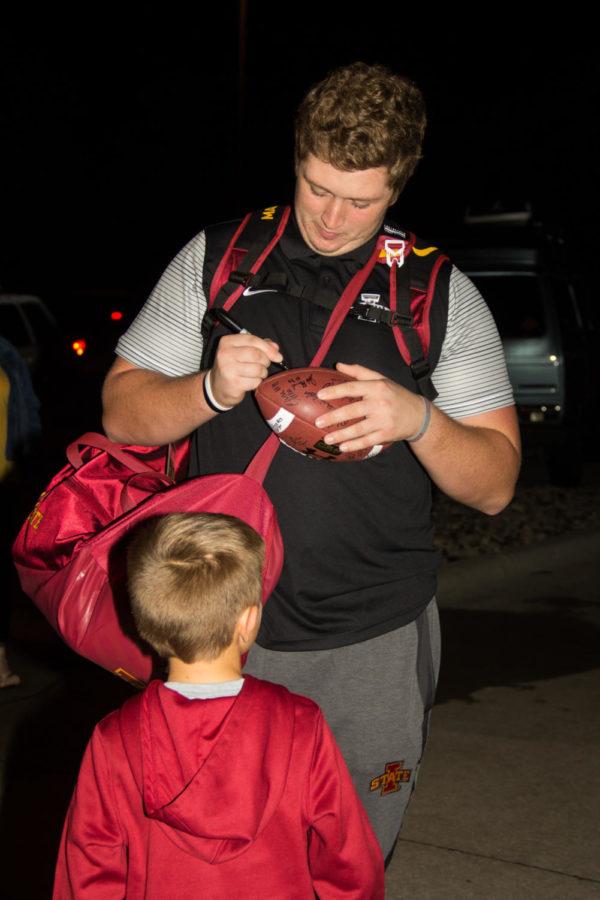 A member of the Iowa State football team signs footballs for fans after arriving back in Ames Oct. 7, 2017, following the Oklahoma football game where Iowa State won 38-31. 