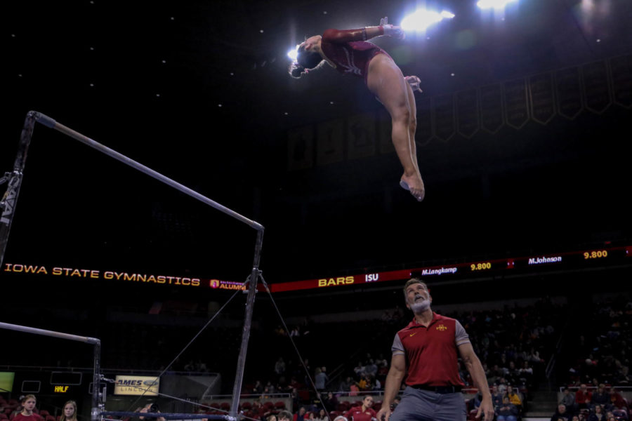 Freshman Maddy Langkamp competes on the bars with assistant coach Nilson Medeiros watching over. The meet was held on Friday, March 15 in Hilton Coliseum with Denver winning 197.225 to 195.925.