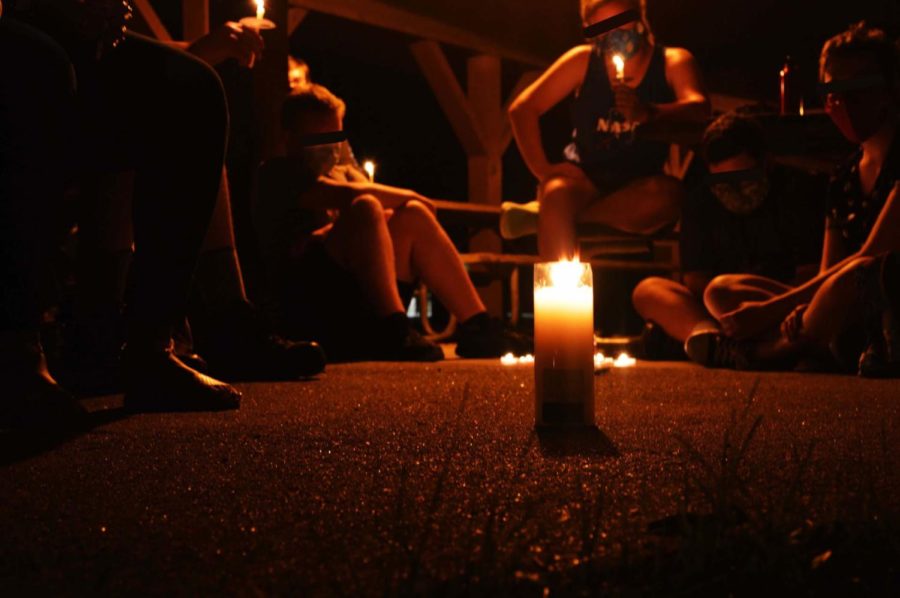 A group of participants sit around a group of candles at a candlelight vigil hosted by Ames Black Lives Matter on Thursday evening.