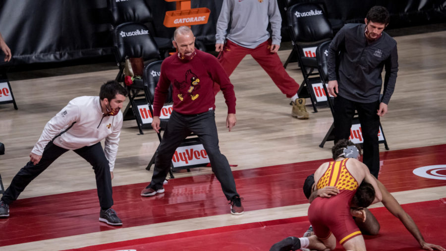 Iowa State Head Coach Kevin Dresser (middle) and assistant coaches Brent Metcalf (left) and Derek St. John (right) look on as Iowa States Isaac Judge wrestles Anthony Valencia of Arizona State on Feb. 14.