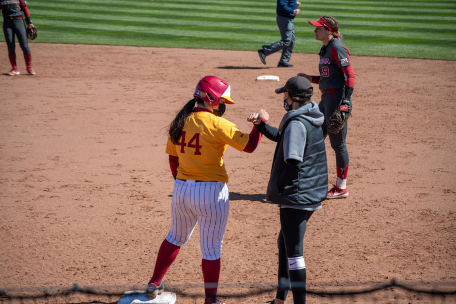 Assistant coach Kate Sinnott gives Mikayla Ramos a forearm bump after she gets on first base against Oklahoma on March 28th.
