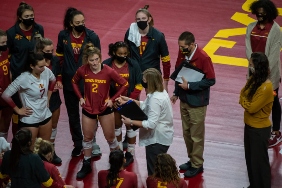 Iowa State volleyball talks during a team huddle, with coaches and players wearing protective masks per the COVID-19 pandemic.
