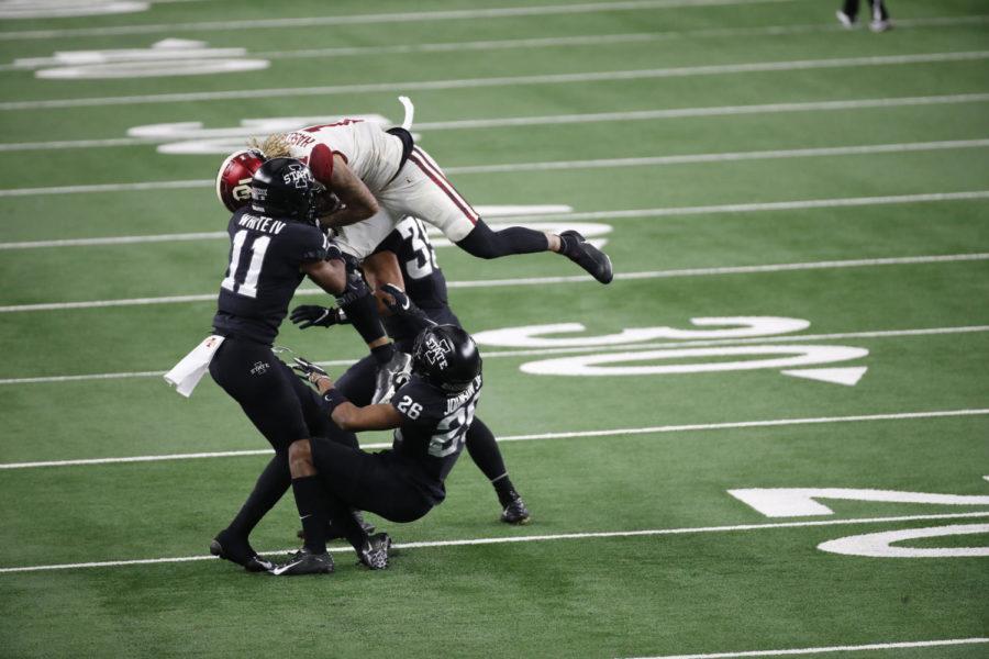 Jadon Haselwood (No. 11) of the Oklahoma Sooners is tackled after a catch by Lawrence White (No. 11), Anthony Johnson (No. 26) and Jake Hummel (No. 35) of the Iowa State Cyclones during the first half of the 2020 Dr. Pepper Big 12 Championship at AT&T Stadium in Arlington, Texas. 