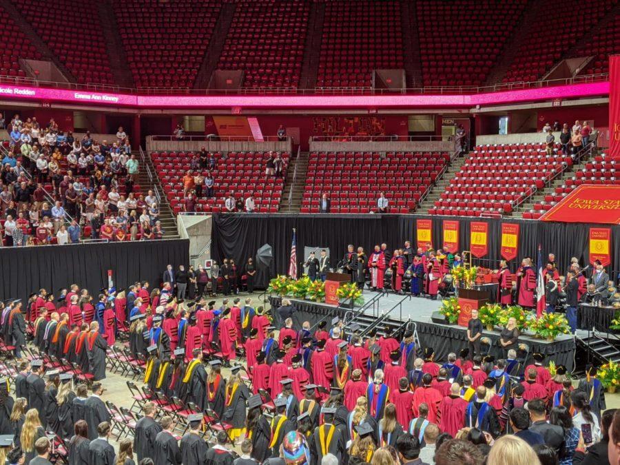 Graduates and members of Iowa States academic community standing during the national anthem.