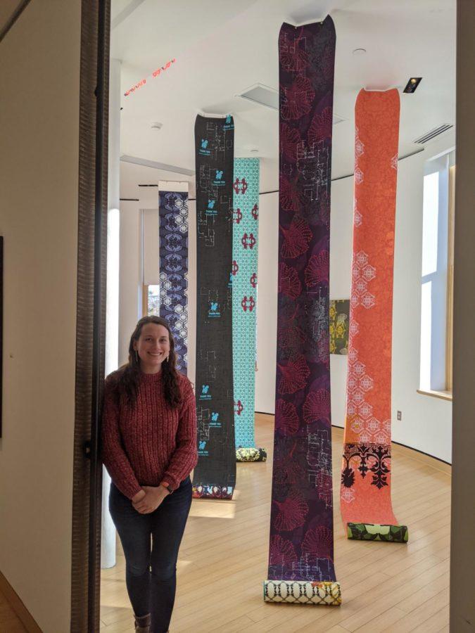 University Museums Curator standing next to the Vibrant Matter scroll installation. All works on loan from Julie Chang and Hosfelt Gallery.