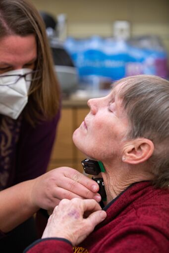 Sensors are applied to participants’ throats for data collection while they talk and eat. Pictured here is Assistant Professor of Kinesiology, Elizabeth Stegemoller, attaching the sensors to Kathy Gundlach’s throat.
