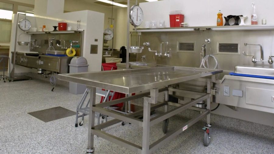 A clean autopsy table at the Iowa Office of State Medical Examiner. On average, Iowa medical examiners complete six autopsies a day. The table has a hole at the end to allow for bodily fluids to be flushed into a drain.