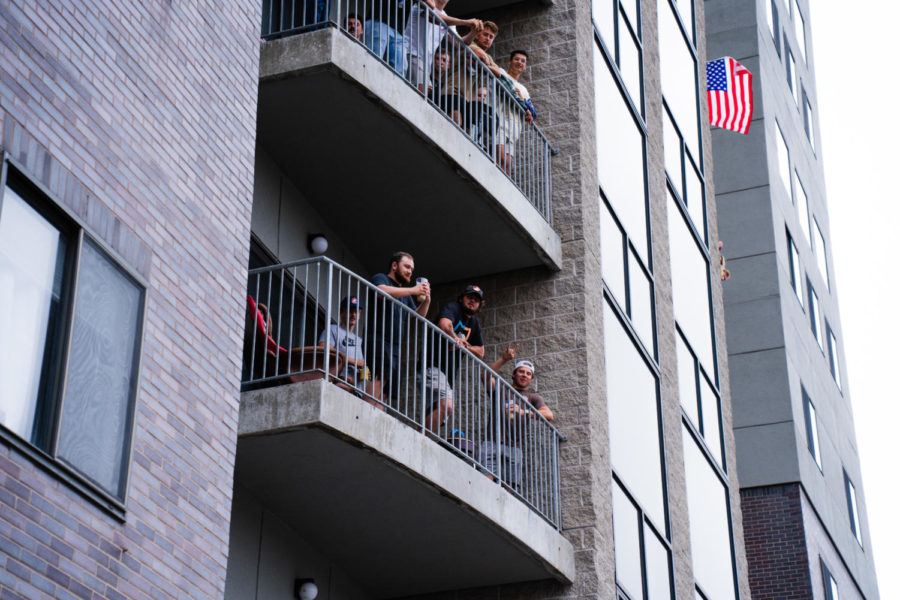 People stand out on balconies looking over Campustown celebrating the Saturday before classes.