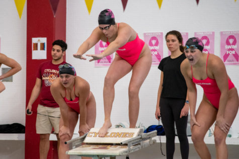 Swimmers prepare to jump off the starting blocks as teammates cheer them on Oct. 30.