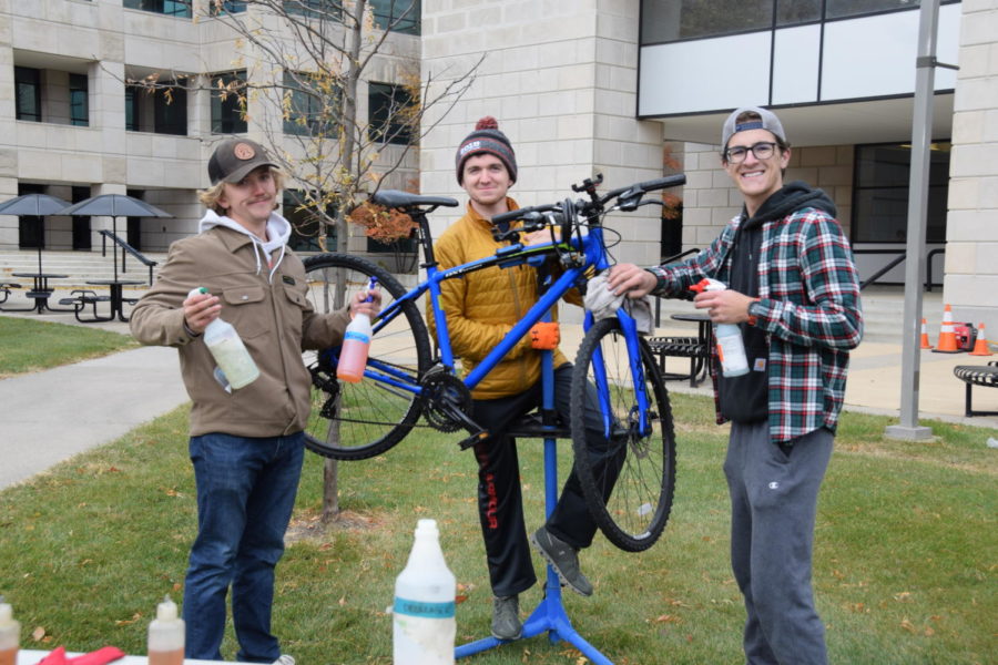 Erik Evans (left) and Evan Baker (right) pictured with one other member of Iowa States Adventure programs while posing with a bike used to demonstrate their bike repair services.