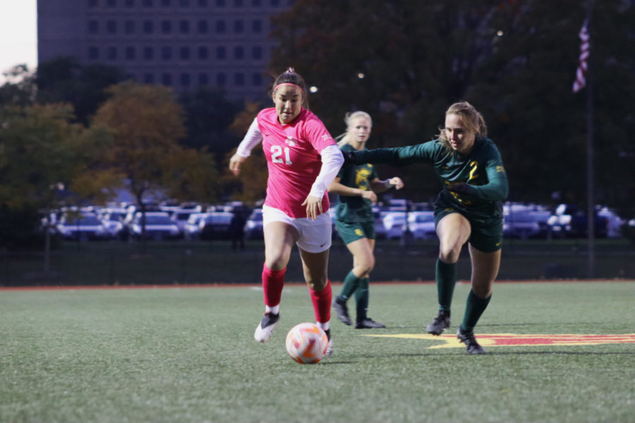 Sophia Thomas pushes the ball up the field with Wallace and Wilson residence halls in the background on Oct. 13.