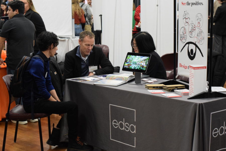 Gonzalo Espinoza, a senior majoring in landscape architecture, pictured sitting and talking with representatives of EDSA, an architectural design firm. Espinoza said the booth’s graphics and the welcoming attitude of the representatives got his attention. 