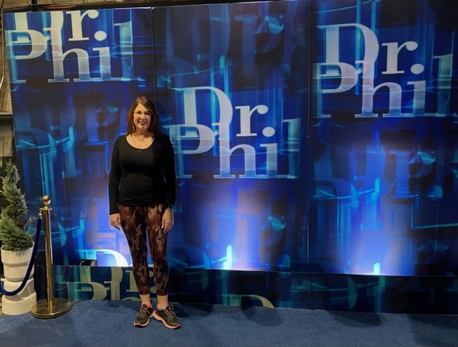 Dr. Susan Stewart poses in front of a Dr. Phil backdrop while appearing on an episode of the show. Courtesy of Dr. Stewart.