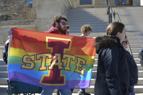 Ethan Rosonke holds an Iowa State pride flag during the LGBTQIA+ walkout on March 1, 2023.