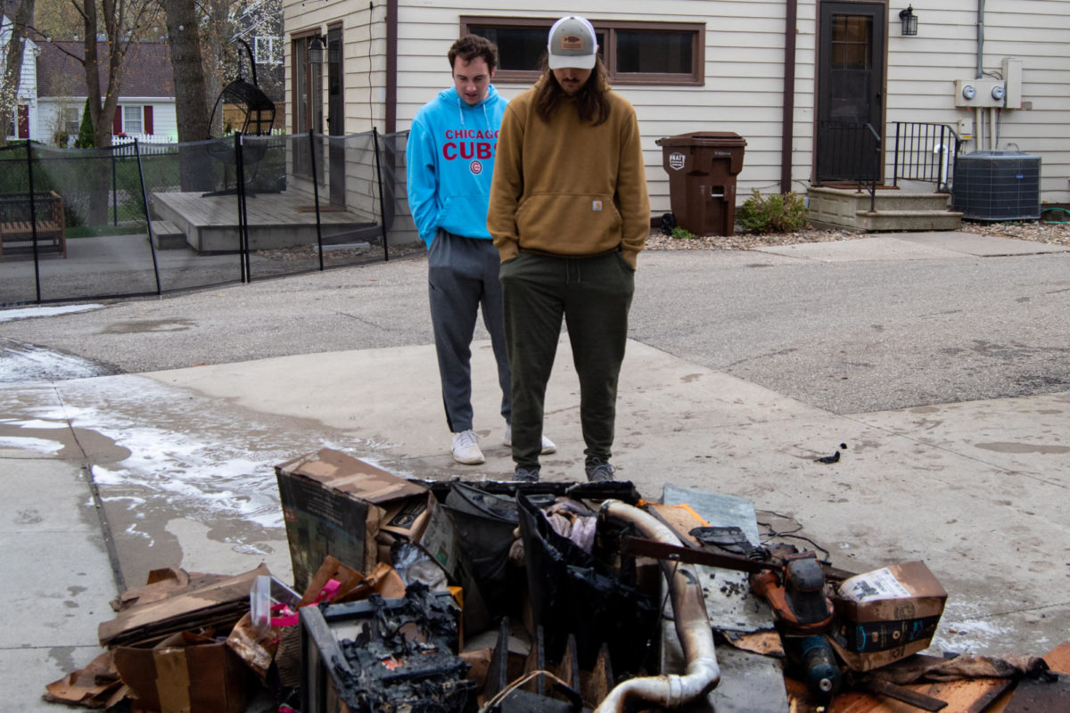 Jonathan Young, left, and Judd Baer, right, two of the four tenants who showed up to the scene, look over a pile of burnt and melted debris after a basement fire broke out on April 21, 2023, at their rented house along Ash Avenue.