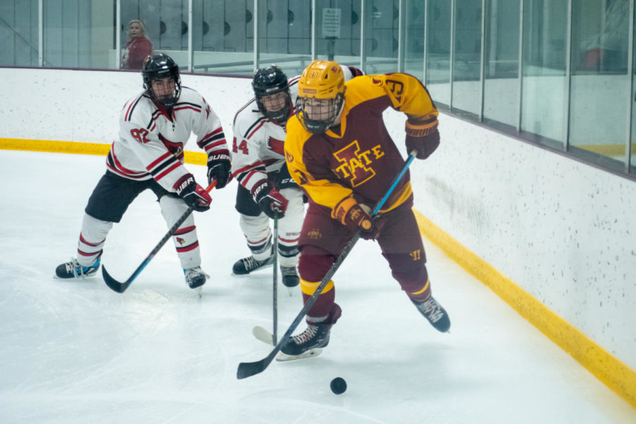 Conner Hunt maneuvers along the boards around two Illinois State University players during the game in the Ames/ISU Ice Arena on October 1, 2021.