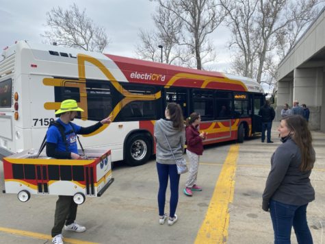 Chief Safety Officer Kevin Gries featured wearing the mini-bus mascot, which has a working horn, turn signals, break lights, headlights and high-beams, as CyRides electric bus ribbon cutting ceremony. 