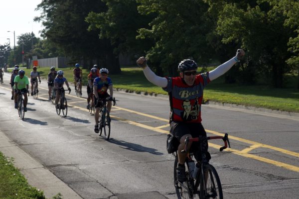 A biker puts both fists in the air along Mortensen Road.