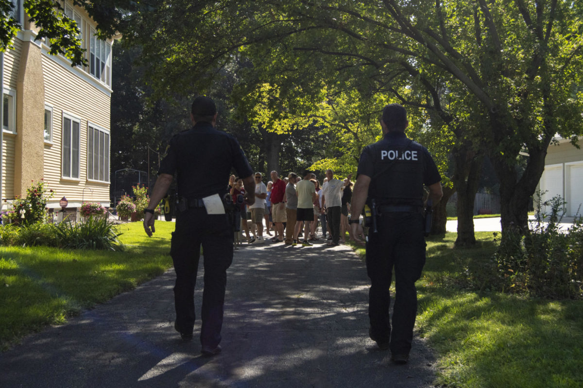 Community Resource Officer Nate Rivera, left, and Detective Andrej Klaric, right, walk up to a backyard party filled with older adults and children during “801 day” on Aug. 19, 2023 in Ames. “We like to use this day to reach out and talk to residents,” Rivera states. “We try to build rapport.”