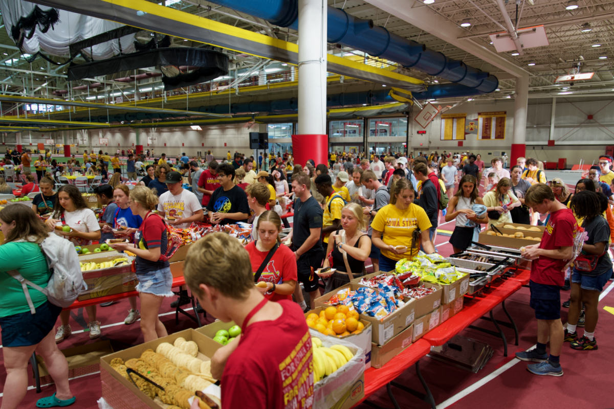 Students line up to fill their plates with burgers, brats, chips and fruit at the Iowa State Welcome Cookout in Lied Rec Center on Aug. 18, 2023.