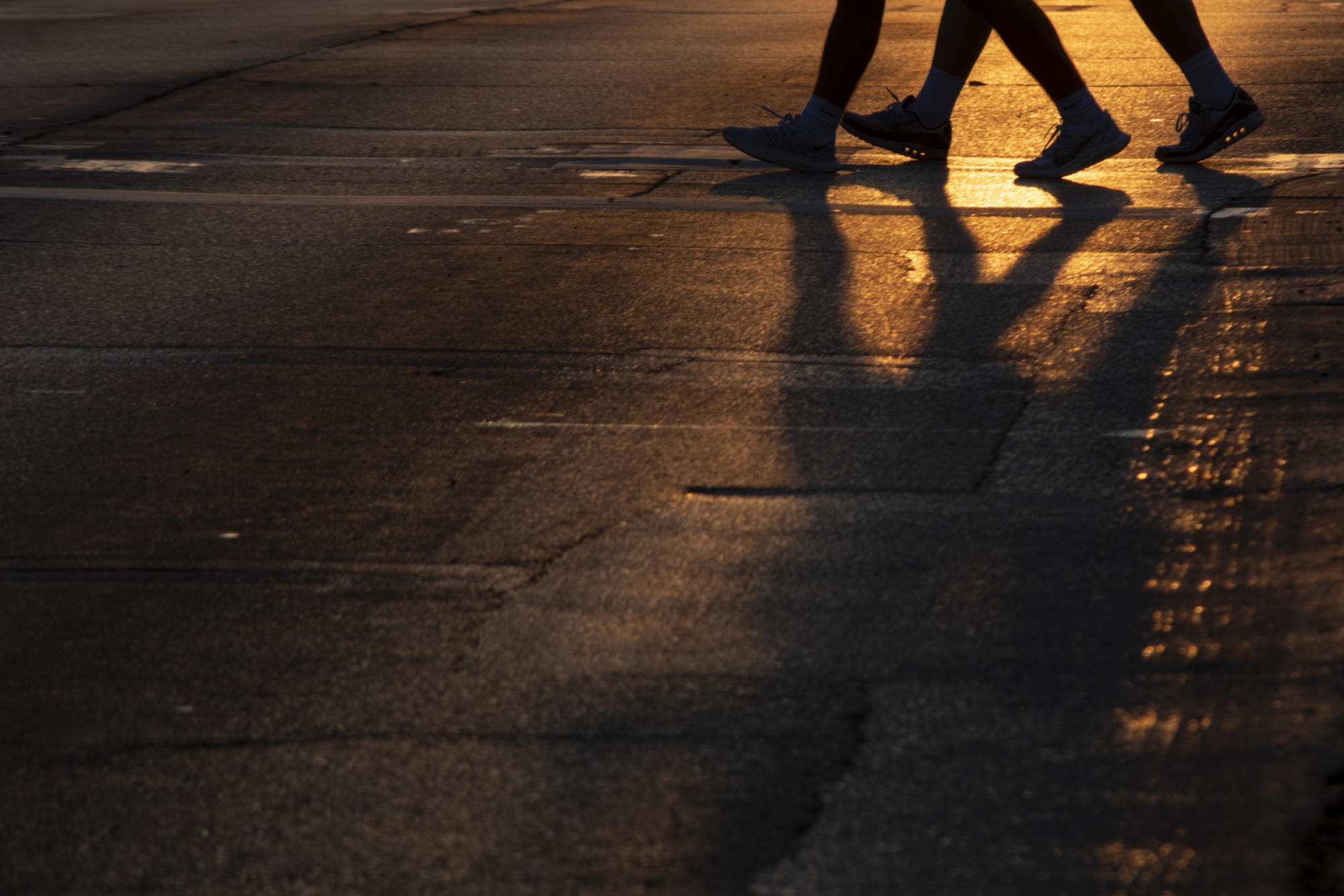 Young adults walk across Lincoln Way as the sun sets on Wednesday, Sept. 20, 2023, in Ames, Iowa.