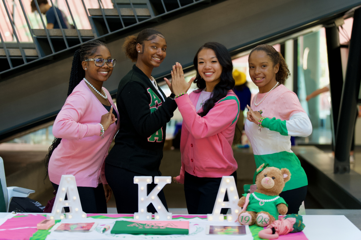 AKA members Olivia Plant, Kyra Lucas, Joann Nguyen and Jasmine Williams posing at their table for the Nation Pan-Hellenic Council Meet the Greeks event in the Student Innovation Center on Sept. 14, 2023.