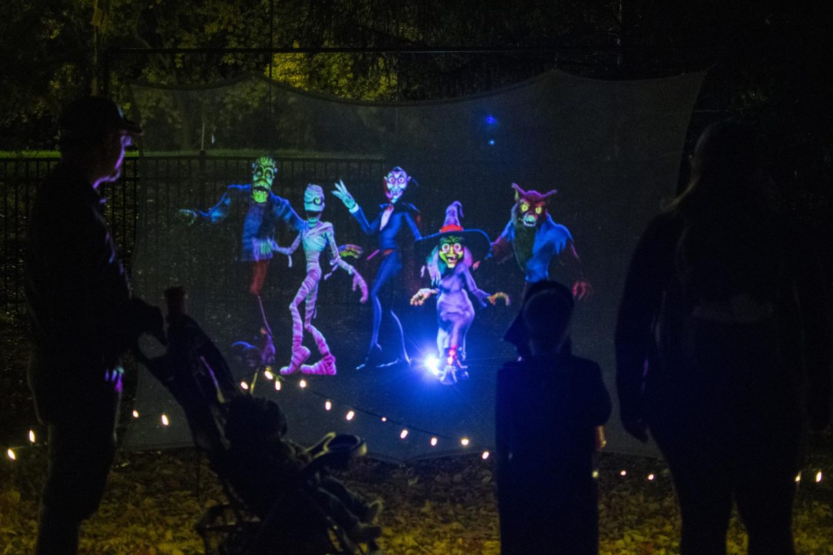 A family attending the Spirits in the Gardens fall celebration watch a projected performance of different characters dancing on Saturday, Oct. 21, 2023, at Reiman Gardens in Ames, Iowa.