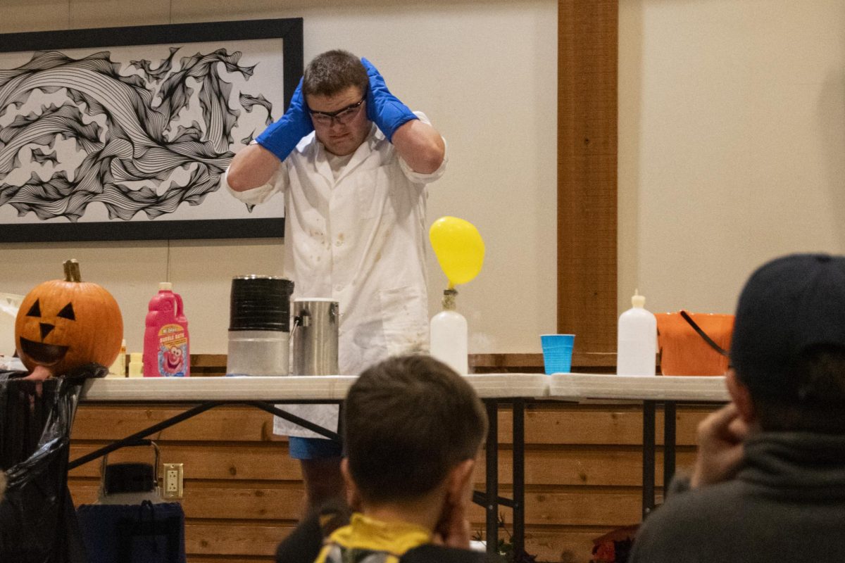 Attendees of the Spirits in the Gardens fall celebration wait for a balloon to pop during Iowa State’s Society of Chemistry Undergraduate Majors science demonstration on Saturday, Oct. 21, 2023, at Reiman Gardens in Ames, Iowa.