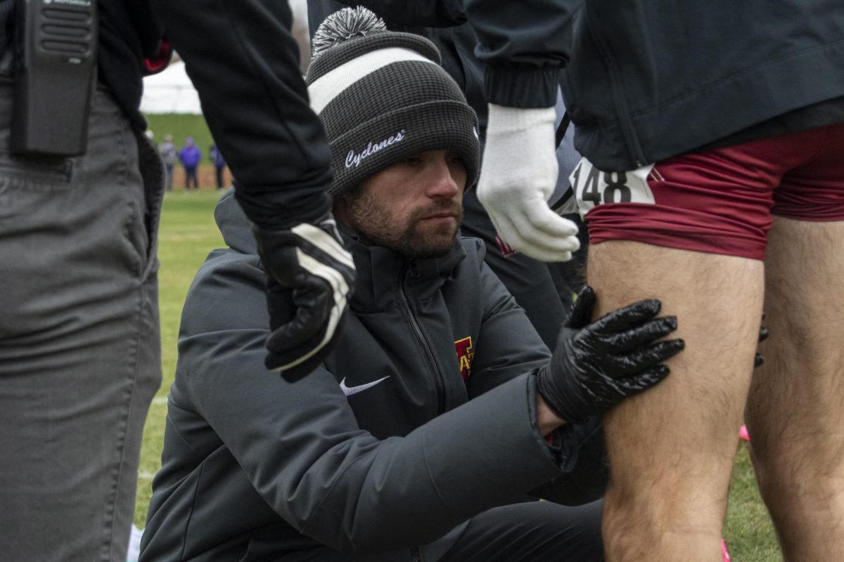 Members of the Iowa State Men’s Cross Country staff apply organic olive oil to the legs of the competitors before the Big 12 Men’s Cross Country Championship on Saturday, Oct. 28, 2023, at the Iowa State University Cross Country Course in Ames, Iowa.